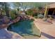 Beautiful freeform pool with rock waterfall feature, surrounded by lush desert landscaping and mature trees at 6591 E Amber Sun Dr, Scottsdale, AZ 85266