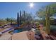 Beautiful freeform pool with rock waterfall feature, surrounded by desert landscaping and multiple cacti at 6591 E Amber Sun Dr, Scottsdale, AZ 85266