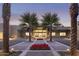 Inviting entrance with well-lit walkway, palm trees, and vibrant red flowers beneath a dusk sky at 7222 E Gainey Ranch Rd # 106, Scottsdale, AZ 85258
