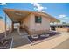 Mobile home with covered patio and carport on a sunny day, landscaped yard with rock and desert accents at 7807 E Main St # Cc105, Mesa, AZ 85207