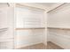 Walk-in closet with white walls and light-colored carpet features multiple shelves and wooden rods for storage at 826 W Devon Dr, Gilbert, AZ 85233