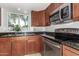 Well-lit kitchen featuring dark granite countertops, stainless steel appliances, and wooden cabinetry, with a view to the backyard at 826 W Devon Dr, Gilbert, AZ 85233
