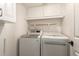 A well-equipped laundry room with white cabinets, open shelving, and modern washer/dryer units at 826 W Devon Dr, Gilbert, AZ 85233