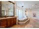 Bathroom featuring a large soaking tub, travertine floors and glass block accents at 8392 E Eagle Feather Rd, Scottsdale, AZ 85266