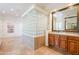 Bathroom with a soaking tub, travertine floors, glass block accents and wood cabinets at 8392 E Eagle Feather Rd, Scottsdale, AZ 85266