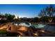 A beautiful pool with a stone waterfall feature and desert views at dusk at 8392 E Eagle Feather Rd, Scottsdale, AZ 85266