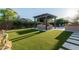 Expansive backyard with a pergola covered seating area, artificial turf, and a grilling station at 9369 W Via Montoya Dr, Peoria, AZ 85383