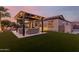Well-lit backyard featuring an outdoor kitchen, pergola, and well-maintained artificial turf at 9369 W Via Montoya Dr, Peoria, AZ 85383