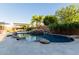 Resort-style pool with a rock waterfall feature, surrounded by lush landscaping and a travertine deck at 9369 W Via Montoya Dr, Peoria, AZ 85383