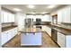 Bright kitchen with stainless appliances, white cabinets, and island with granite countertop at 10031 W Hess St, Tolleson, AZ 85353
