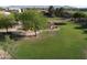Scenic aerial view of a neighborhood park with lush green grass, mature trees, a gazebo, a playground, and walking path at 10031 W Hess St, Tolleson, AZ 85353