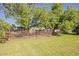 Backyard view showcasing the large, fenced yard, mature trees, and green lawn at 125 N Fraser E Dr, Mesa, AZ 85203