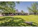 Vast backyard with well-maintained lawn, mature trees, outdoor seating and games ideal for entertaining and recreation at 125 N Fraser E Dr, Mesa, AZ 85203