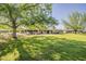 Expansive backyard featuring lush green lawn, mature trees, covered patio, and game area, perfect for outdoor living at 125 N Fraser E Dr, Mesa, AZ 85203