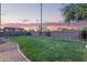 Green backyard with lush lawn, landscaped borders, and a beautiful desert sunset sky at 14556 W Shaw Butte Dr, Surprise, AZ 85379