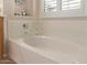Close-up of a pristine white bathtub with chrome fixtures and shuttered window at 14556 W Shaw Butte Dr, Surprise, AZ 85379