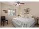 Cozy bedroom with a ceiling fan, a bed with decorative pillows, and plantation shutters at 14556 W Shaw Butte Dr, Surprise, AZ 85379