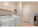 Functional laundry room with appliances, storage shelf, and door to another part of the house at 14556 W Shaw Butte Dr, Surprise, AZ 85379