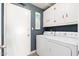 Functional laundry room features a washer, dryer, white cabinets, and a door leading outside at 15212 N 53Rd St, Scottsdale, AZ 85254