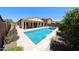 Well-maintained backyard featuring a sparkling pool, covered patio, and lush landscaping at 17947 W Jojoba Rd, Goodyear, AZ 85338