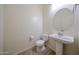 Powder room featuring a white pedestal sink, toilet, tiled floors, and a circular mirror at 17947 W Jojoba Rd, Goodyear, AZ 85338