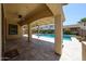 Inviting covered patio with stone floors, ceiling fan, and backyard views at 17947 W Jojoba Rd, Goodyear, AZ 85338