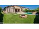 Landscaped backyard featuring a fire pit, artificial grass, and covered patio at 18003 W Carmen Dr, Surprise, AZ 85388