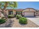 Single-story home with desert landscaping, shade tree, and two-car garage on a sunny day at 18003 W Carmen Dr, Surprise, AZ 85388