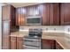 The kitchen features granite countertops, rich wood cabinetry, and stainless-steel appliances at 18003 W Carmen Dr, Surprise, AZ 85388