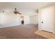 Expansive living room with neutral carpet, ceiling fan, and easy access to the kitchen at 18003 W Carmen Dr, Surprise, AZ 85388
