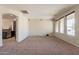 Spacious living room with view to the kitchen, neutral carpet, and bright windows at 18003 W Carmen Dr, Surprise, AZ 85388