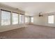 Expansive living room featuring neutral carpet, light-filled windows and an overhead ceiling fan at 18003 W Carmen Dr, Surprise, AZ 85388