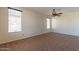 Spacious living room featuring neutral carpet, ceiling fan, and bright natural light at 18003 W Carmen Dr, Surprise, AZ 85388