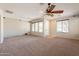 Large living area with neutral carpet, ceiling fan, and multiple windows for natural light at 18003 W Carmen Dr, Surprise, AZ 85388