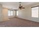 Bright and airy living room with neutral carpet, ceiling fan, and multiple windows at 18003 W Carmen Dr, Surprise, AZ 85388