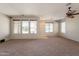 Large living room with neutral carpet, ceiling fan, and lots of windows for natural light at 18003 W Carmen Dr, Surprise, AZ 85388