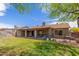 Backyard with lawn, covered patio featuring an outdoor grill, and mature shade trees at 18016 N 145Th Ave, Surprise, AZ 85374