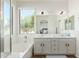 Bathroom featuring double sink vanity, large tub, and bright window allowing lots of natural light at 18414 W La Mirada Dr, Goodyear, AZ 85338