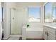 Bright bathroom features a glass enclosed shower, large tub, and vanity with neutral finishings at 18414 W La Mirada Dr, Goodyear, AZ 85338