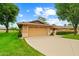 Single-story home featuring an attached two-car garage, manicured lawn and mature trees under a sunny sky at 19053 N Lakeforest Dr, Sun City, AZ 85373