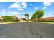 Wide street view of well-maintained homes with mature trees under a bright blue sky with scattered clouds at 19053 N Lakeforest Dr, Sun City, AZ 85373
