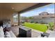 Inviting backyard featuring a well-maintained artificial lawn, brick patio, and comfortable seating area at 1906 N 140Th Dr, Goodyear, AZ 85395