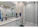 Bathroom featuring double sinks, a large mirror, and a glass-enclosed shower at 1906 N 140Th Dr, Goodyear, AZ 85395