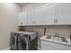 Efficient laundry room with a stainless steel sink and extra white cabinet storage above the washer and dryer at 1906 N 140Th Dr, Goodyear, AZ 85395
