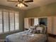 Cozy bedroom with ceiling fan, shuttered windows, and a bed with decorative pillows at 20376 N Coronado Way, Surprise, AZ 85374