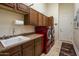 Well-organized laundry room with custom cabinets, countertop space, sink, and modern red washer and dryer at 29619 N 142Nd Pl, Scottsdale, AZ 85262