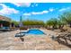 Backyard pool area features a stone-tile patio with lounge chairs and desert landscaping under a bright, sunny sky at 29619 N 142Nd Pl, Scottsdale, AZ 85262