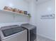 Laundry room with gray front loading washer and dryer, baskets on shelves, and decorative laundry sign at 4150 S Neutron --, Mesa, AZ 85212