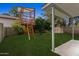 Backyard featuring a wooden play structure, lush green grass, and a covered patio area, perfect for Gathering fun at 440 N New Hvn, Mesa, AZ 85205