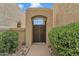 Stucco wall with an arched gate and wrought iron door, framed by lush green bushes and desert landscaping at 4545 E Wescott Dr, Phoenix, AZ 85050